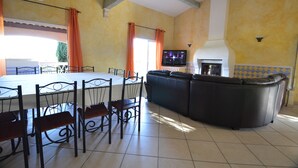 A dining area with a large table and chairs, a sofa, and a television. - Luxury villa with view of the putting green - Gulf of Saint-Tropez (Sainte-Maxime)