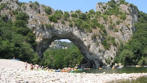A natural rock arch formation with a river flowing through it, surrounded by greenery and rocky terrain. - Chalet Cévennes, France, Gard, Ardèche, pool, calm, large garden, activities (Le Martinet)