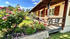 A rustic wooden building with a porch, surrounded by lush greenery and blooming flowers. - Chalet Cévennes, France, Gard, Ardèche, pool, calm, large garden, activities (Le Martinet)