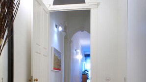 Un pasillo con suelo de madera, puertas blancas y un arco.