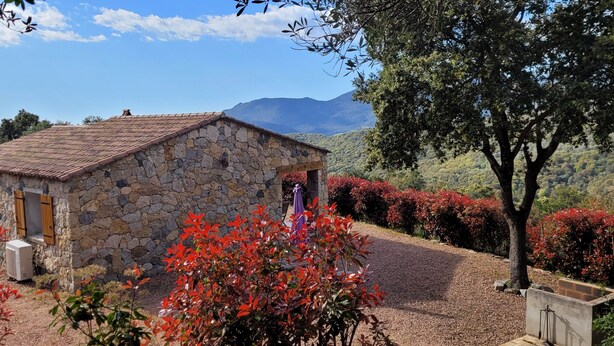 A stone building with a tiled roof, surrounded by red foliage and a gravel path. - Dry stone cottage with outdoor spa, quietness guaranteed (Granace)