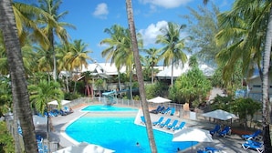 Un área de piscina con sillones reclinables azules y palmeras.