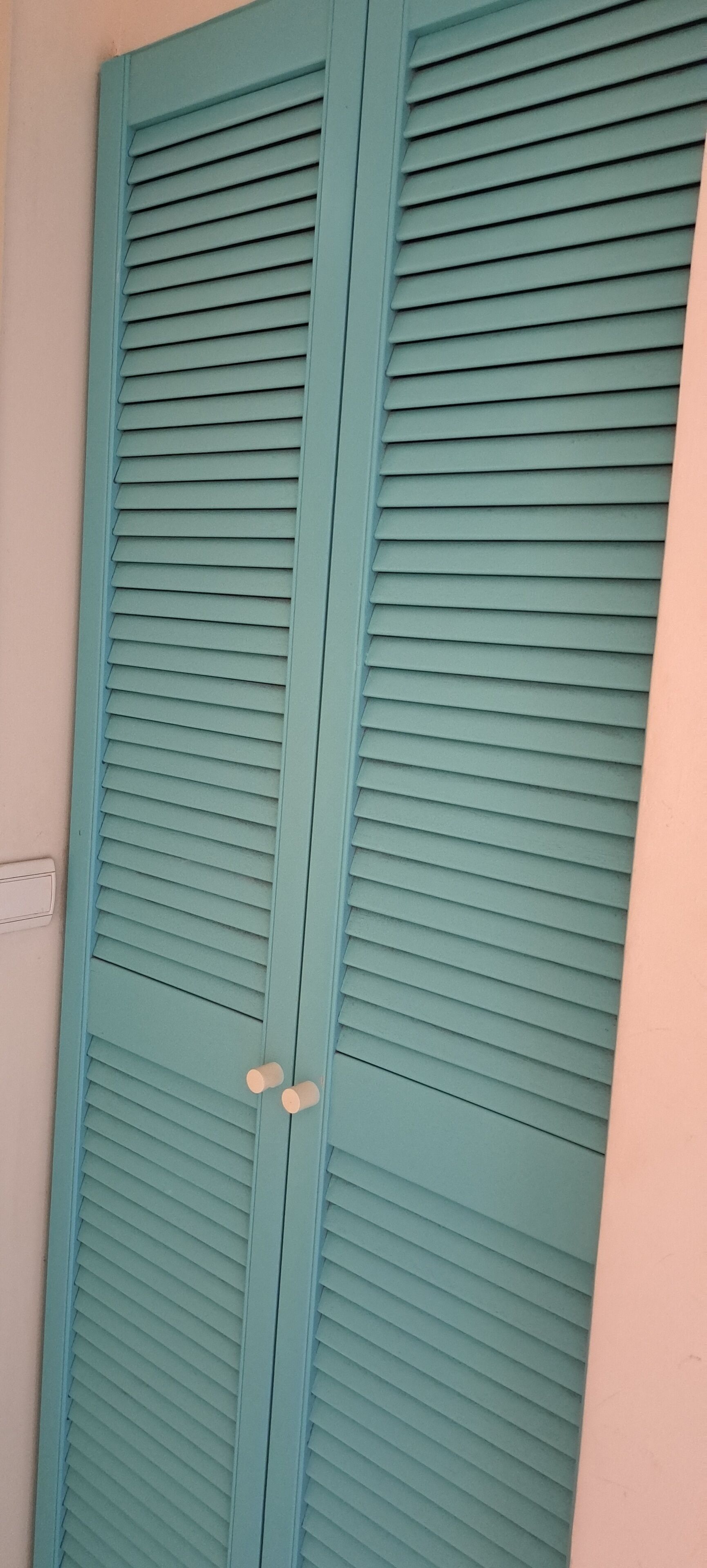A teal-colored sliding door with a handle, likely leading to a room or closet.