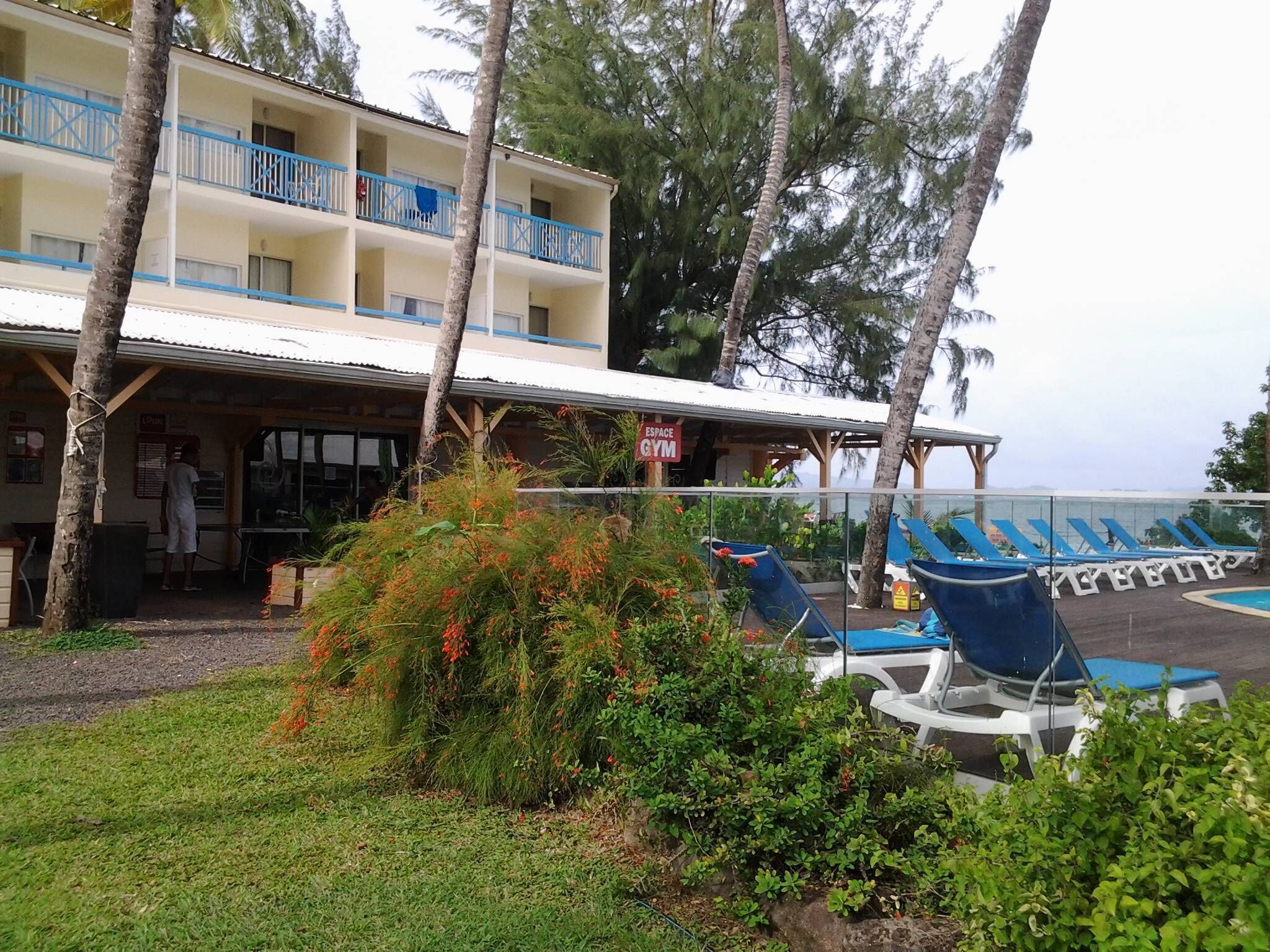 A hotel with a gym, outdoor seating, and a pool area.