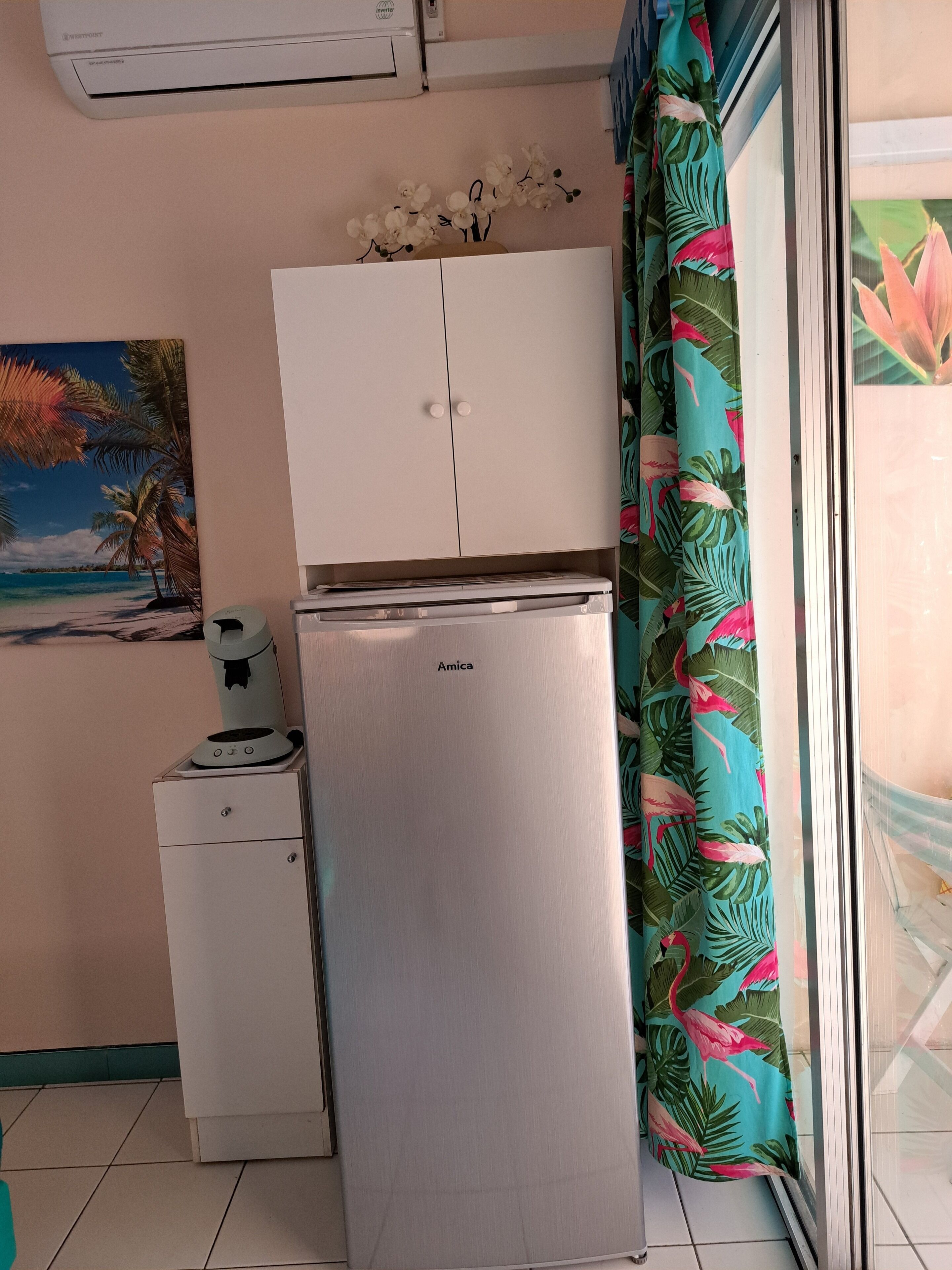 Une cuisine compacte comprenant un réfrigérateur, un petit placard et une machine à café.