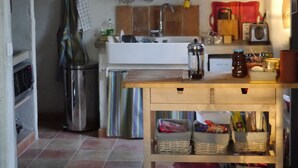 Una cucina compatta con lavandino, un piccolo piano di lavoro e uno scaffale con barattoli e utensili da cucina.
