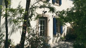 Un edificio con facciata bianca, persiane blu e un piccolo balcone.