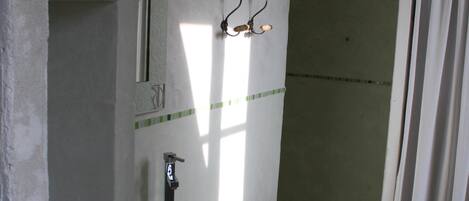 A bathroom with a glass sink, a shower, and a mirror.