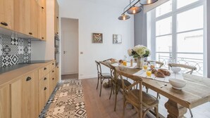 Una cuina moderna amb armaris de fusta, una taula de dinar preparada per l'esmorzar i grans finestres.