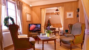 Una sala de estar acogedora con televisor, árbol de Navidad y muebles de madera.