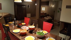 Un comedor con una mesa de madera dispuesta para una comida, rodeada de sillas rojas.