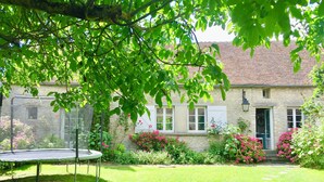 A stone house with a garden, a trampoline, and a stone pathway.