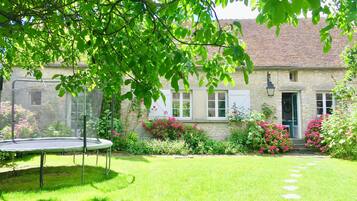 Escape to a serene garden oasis with a well-manicured lawn, beautiful flowers, and a charming entrance.