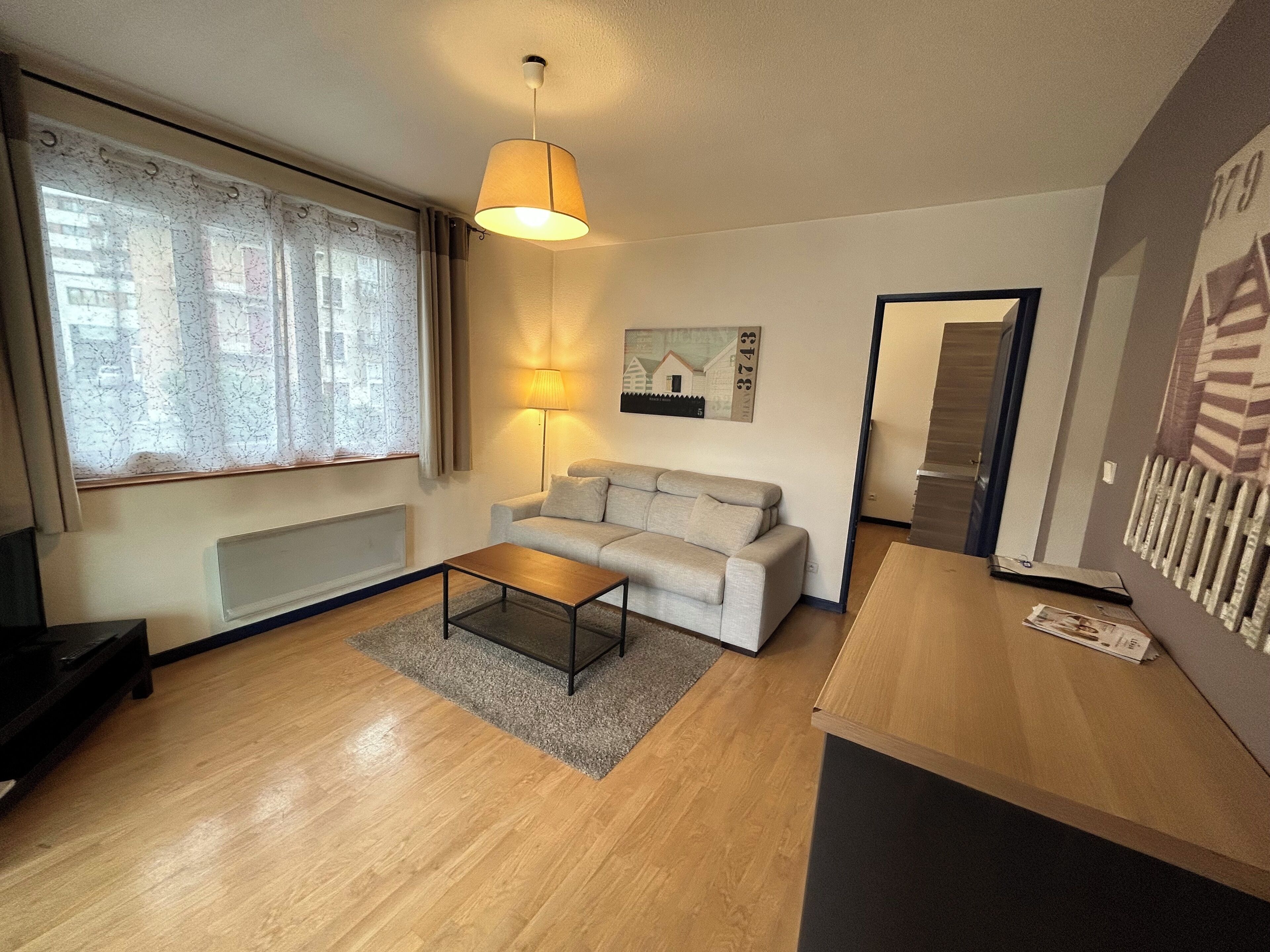Un salon moderne avec un canapé, une table basse, une lampe et un tableau au mur.