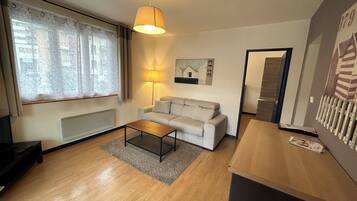 Un salon moderne avec un canapé, une table basse, une lampe et un tableau au mur.