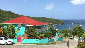 Une maison à deux étages avec un toit rouge, des murs turquoise et un balcon.