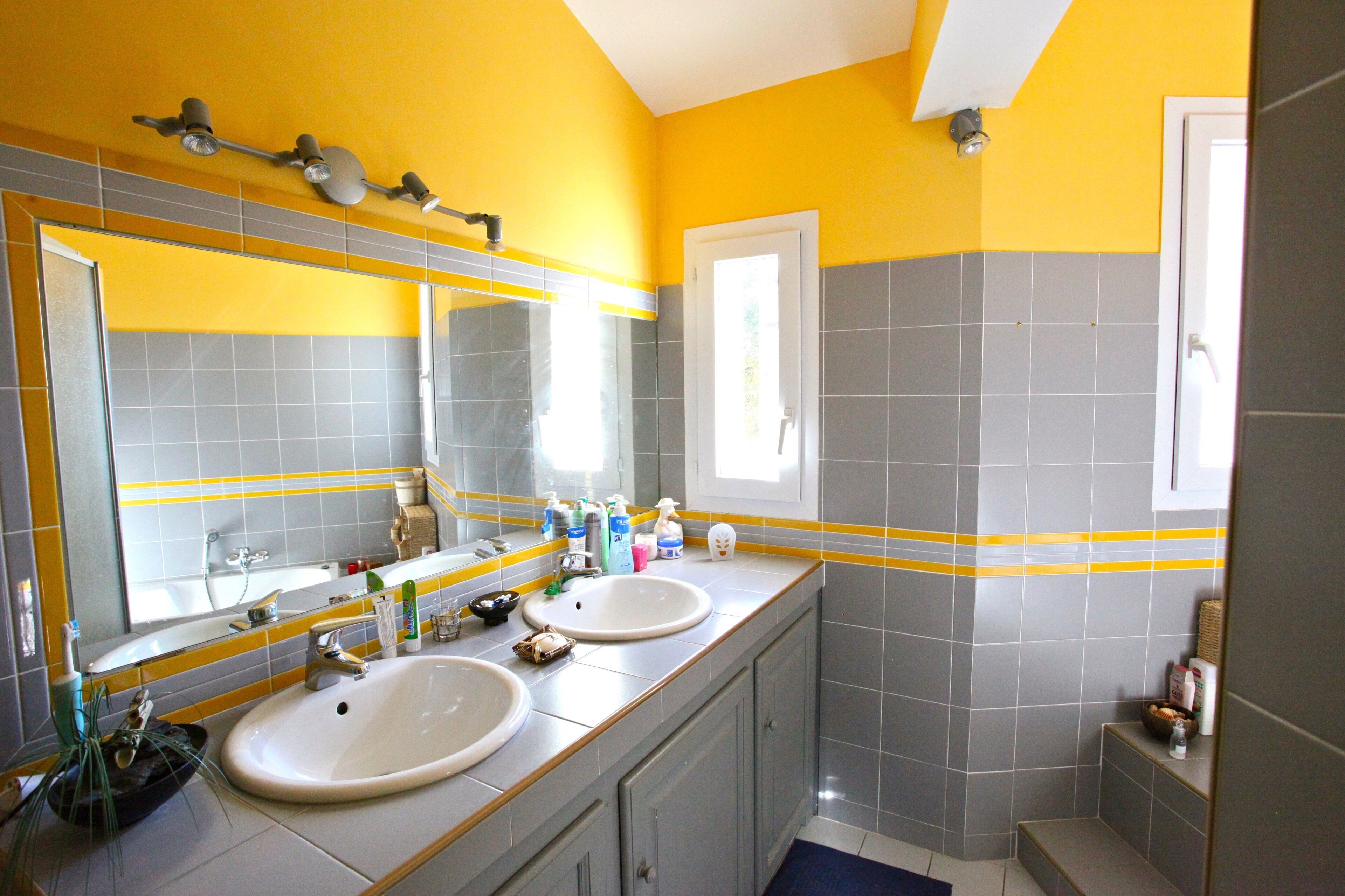 A bathroom with two sinks, a large mirror, and a shower area.