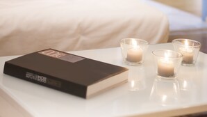 Ein ordentlich bestellter Nachttisch mit einem Buch und vier brennenden Kerzen.