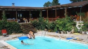 Ein Schwimmbecken mit einer Holzterrasse und Liegestühlen.
