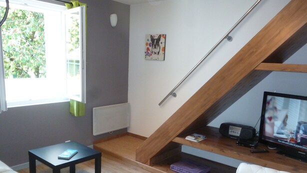 A living room with a wooden staircase, a television, a sofa, and a small table. - APARTMENT FOR 2 OR 3 PERS THONON CENTER (Thonon-Les-Bains)
