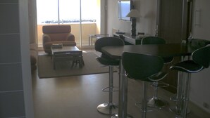 A dining area with a table and chairs, a sofa, and a television on the wall. - valras-plage luxury apartment top floor first line  (Valras-Plage)