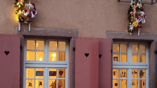 Ein Gebäude mit rosafarbenen Fensterläden, verzierten Fenstern und herzförmigen Aussparungen an der Wand.