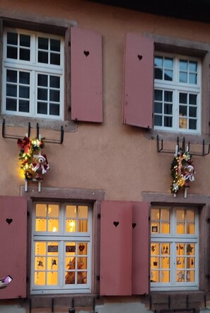 Un bâtiment aux volets roses, aux fenêtres décorées et aux motifs en forme de cœur découpés dans les murs.