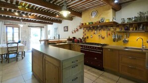Una cocina con una isla central, armarios de madera, una estufa y varios utensilios de cocina colgados en la pared.