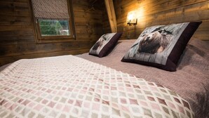 Un dormitorio acogedor con una cama grande, dos almohadas, una ventana con vistas y una lámpara fijada a la pared.