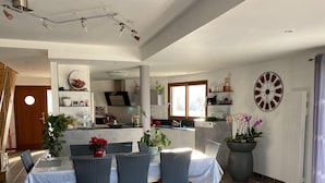 A modern kitchen with a dining area, featuring a large dining table, chairs, and a potted plant. - House with sea view, walking distance to the beach, enclosed garden (Trégunc)