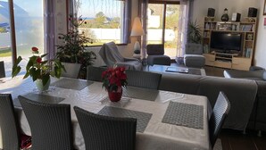 A living room with a dining area, a sofa, a television, and a bookshelf. - House with sea view, walking distance to the beach, enclosed garden (Trégunc)