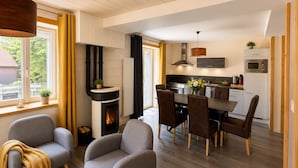 Una cocina moderna con una isla central, comedor con sillas y una chimenea.