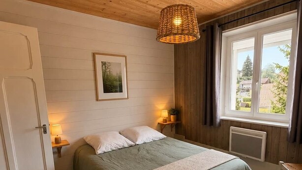 Un dormitorio con cama, lámparas de noche, una ventana, una puerta y un tapete tejido.