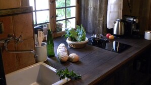 Une cuisine rustique avec un plan de travail en bois, un évier, une bouilloire et une fenêtre donnant sur un paysage verdoyant.