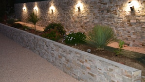 Un mur de pierre agrémenté de luminaires encastrés et d’une variété de plantes.