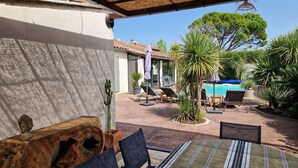 A patio area with a pool, lounge chairs, and a wooden table. - house in provence between Saint Remy and Avignon with swimming pool for 6 people (Graveson)