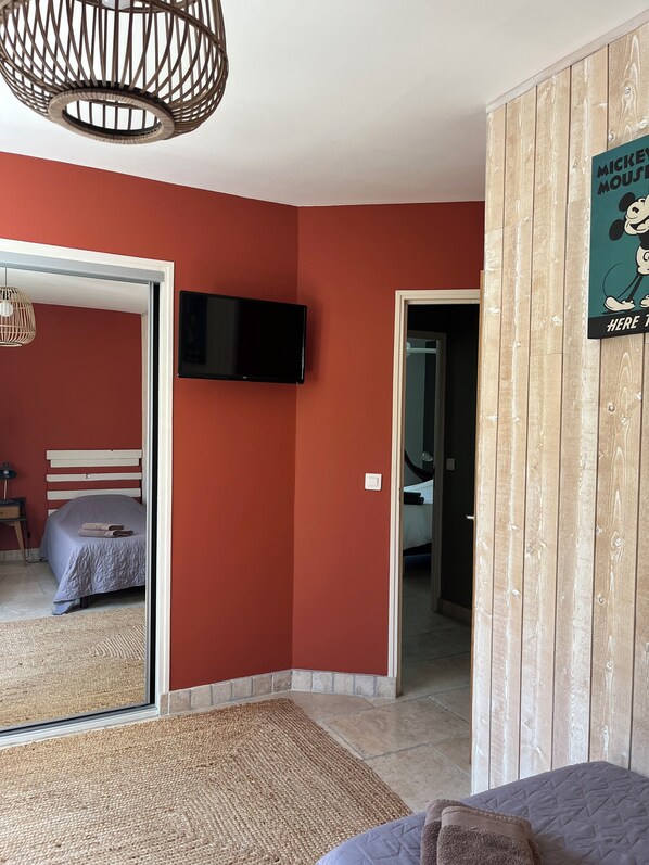 Une chambre avec un lit, une télévision et un mur en bois orné d’une affiche de Mickey Mouse.