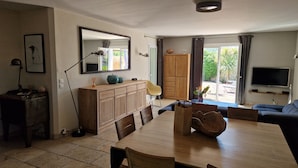 A modern living space with a dining area, a wooden cabinet, a TV, and a view of the outdoors. - house in provence between Saint Remy and Avignon with swimming pool for 6 people (Graveson)