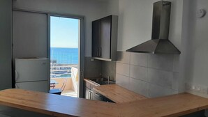 Una cocina moderna con encimera de madera, horno empotrado y vistas al mar a través de un ventanal corredero.