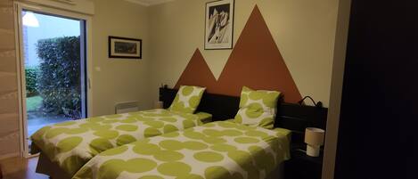 A bedroom with two beds, each with green and white polka dot bedding, a brown headboard, and a framed picture on the wall.