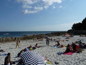 Ein überfüllter Strand mit Menschen, die sich sonnen und schwimmen.