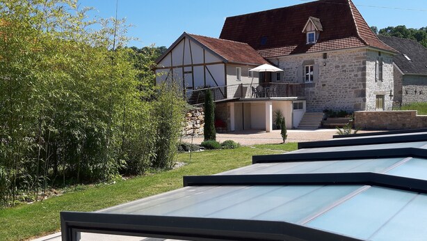 Ein modernes Haus mit Naturstein-Fassade, einem Balkon und einem Poolbereich.