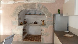 Eine Küche mit einem Steingewölbe, einem Backsteinofen und einem modernen Kühlschrank.