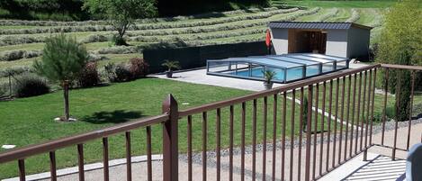 Une terrasse avec une piscine, un petit abri de jardin et une vue sur un paysage verdoyant.