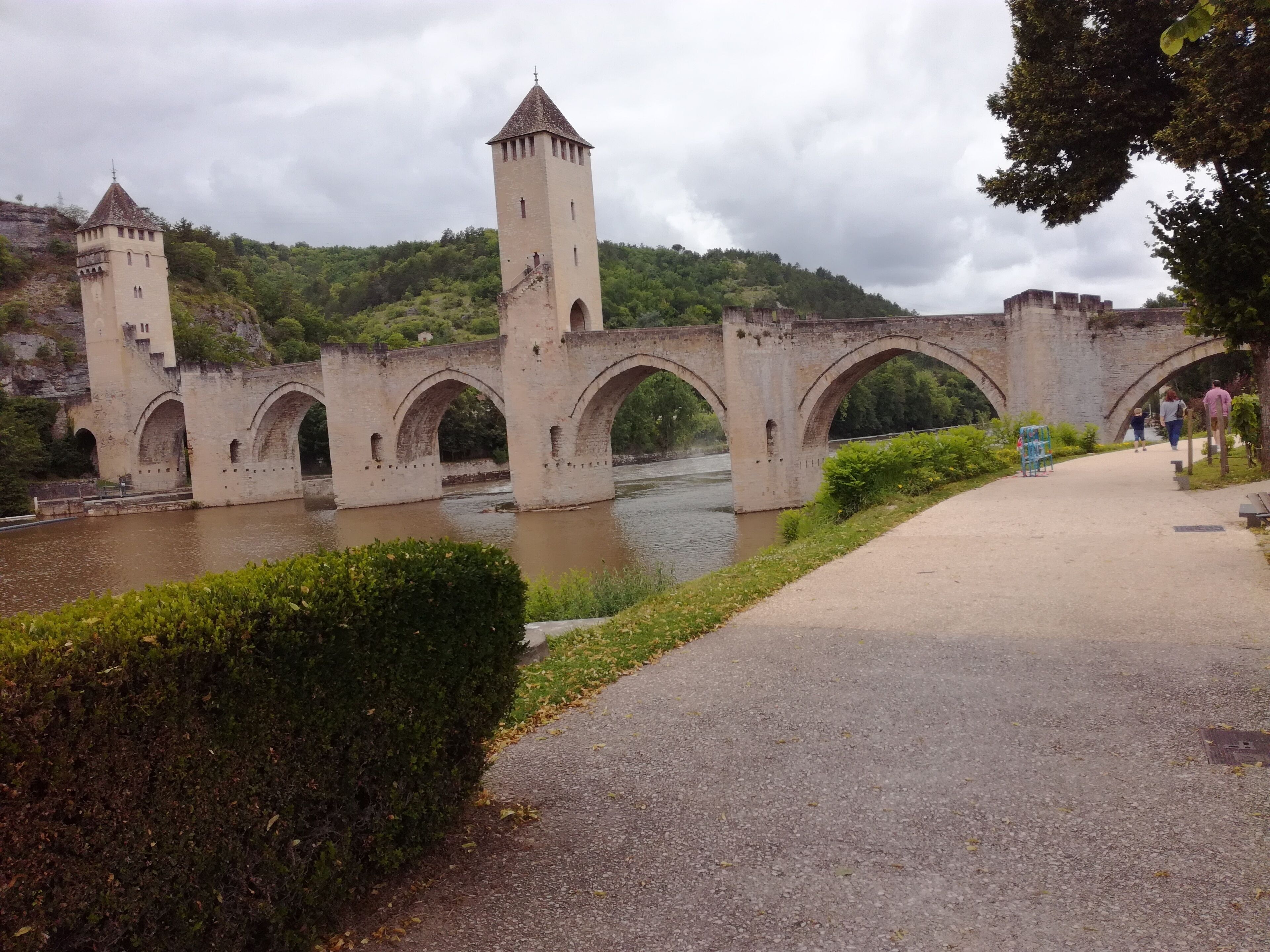A stone bridge with two towers and multiple arches over a river.