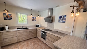 Una cucina moderna con mobili in legno, forno a microonde integrato, cappa aspirante in acciaio inossidabile e una finestra vista verde.