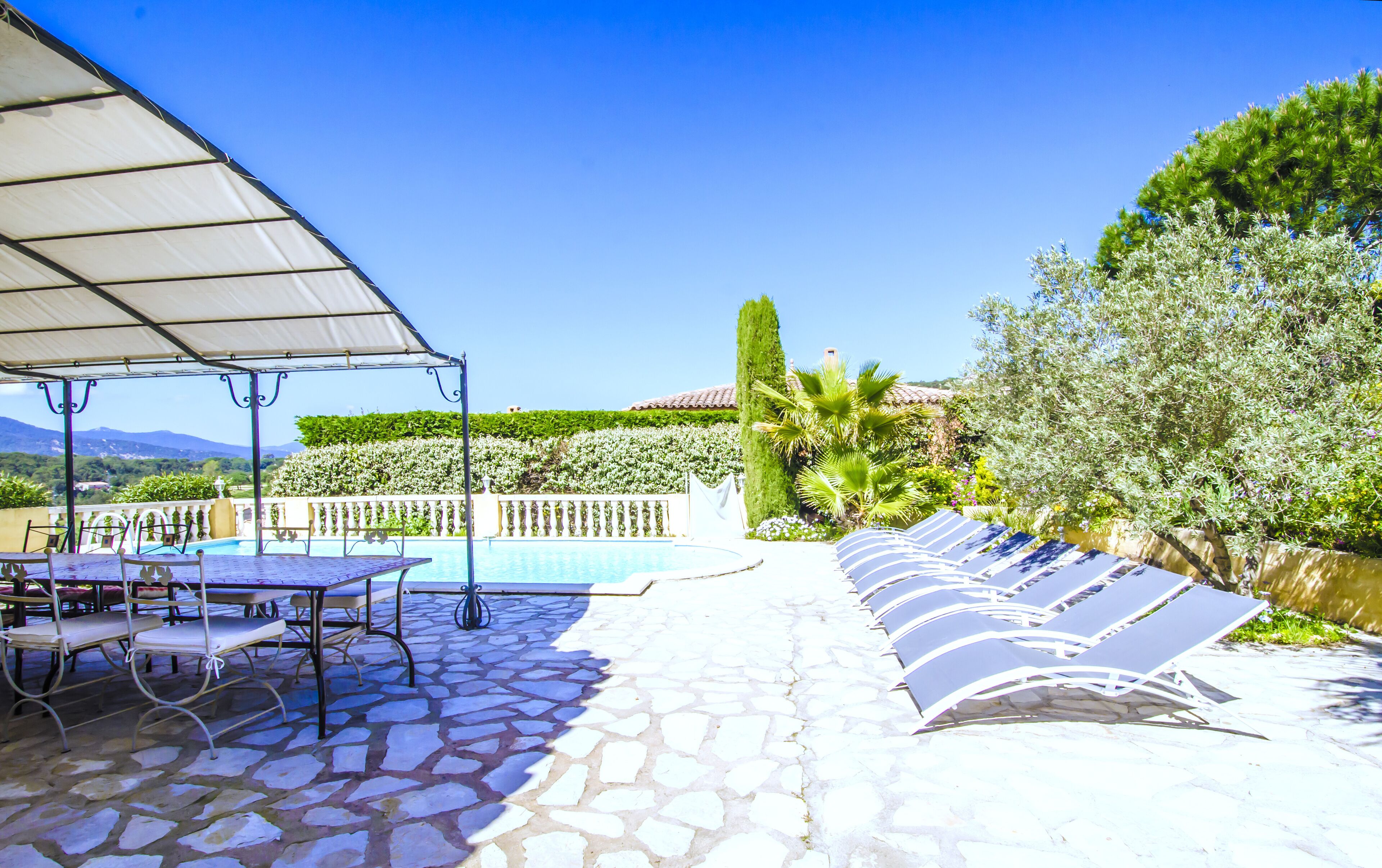 Zona junto a la piscina con un espacio de descanso cubierto, una piscina y vistas del paisaje.