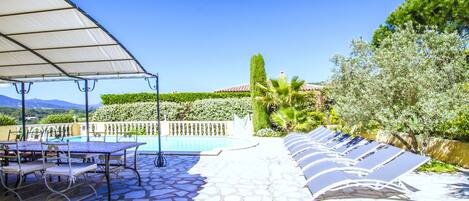 Zona junto a la piscina con un espacio de descanso cubierto, una piscina y vistas del paisaje.