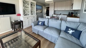 En moderne stue med en grå sofa, et glasbord og et hvidt skab med glasdøre.