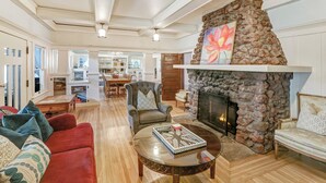 A spacious living room with a stone fireplace, a red sofa, a round coffee table, and a comfortable armchair. - Clean & Spacious-Walk to the Fairmont, great restaurants, coffee shops and wine (Sonoma)